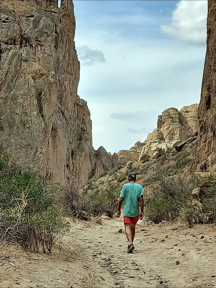 Persona caminando por un cañón de paredes de roca